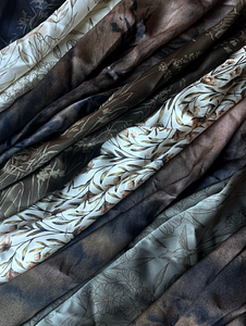 Assorted silk scarves lined up together featuring Linsey Gray's original charcoal artwork and hand-drawn botanical patterns